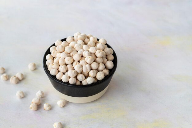 Pois chiches blancs dans un bol sur fond de bois blanc