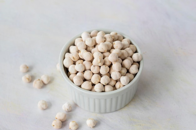 Pois chiches blancs dans un bol sur fond de bois blanc