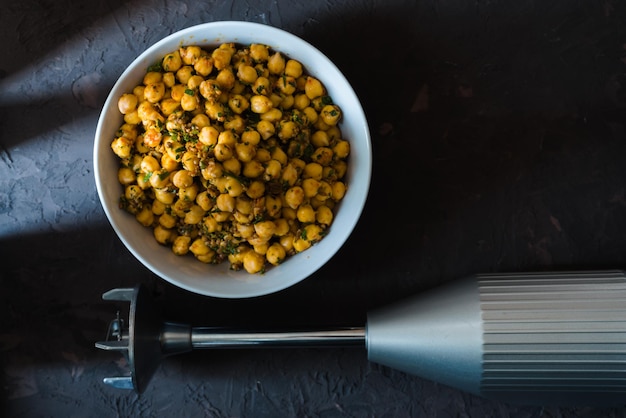 Pois chiches dans un bol en céramique et mélangeur pour faire de l'espace libre de falafel