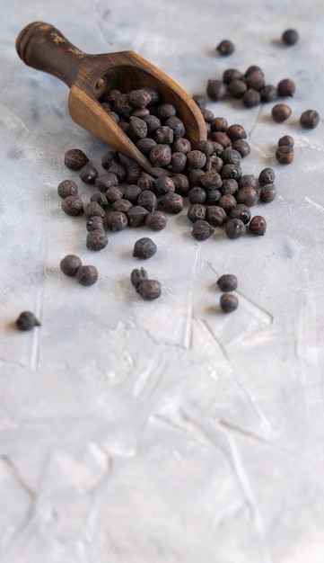 Pois chiches noirs secs des Pouilles et de la Basilicate en Italie sur la boule en bois sur une table grise avec espace de copie, gros plan