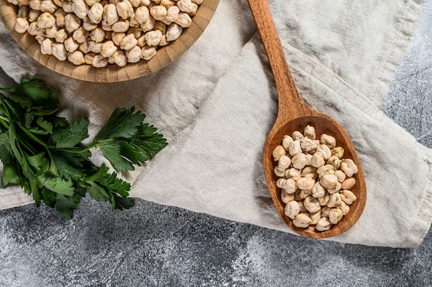 Pois chiches séchés dans une cuillère en bois. Nourriture végétarienne saine. Fond gris. Vue de dessus