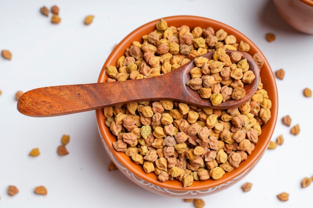 Pois chiches secs dans un bol et une cuillère en bois.