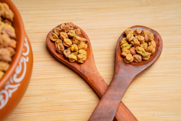 Pois chiches secs dans un bol et une cuillère en bois.