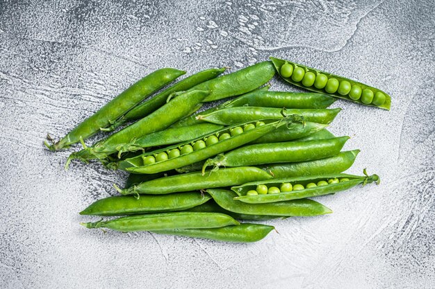 Pois et cosses de pois verts sur une table de cuisine. Fond blanc. Vue de dessus.