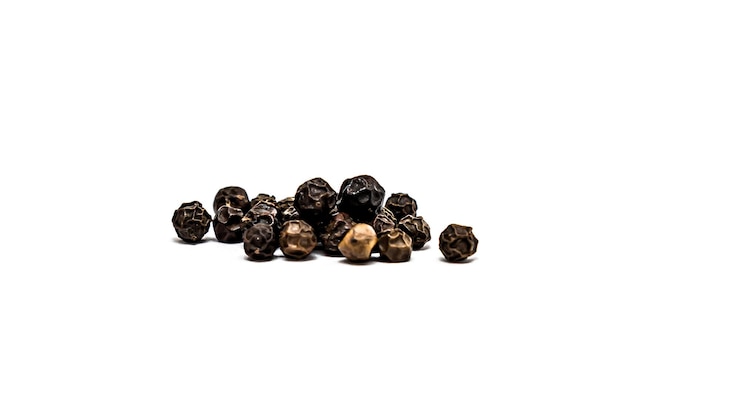 Photo des pois d'épices noires en gros plan sur un fond blanc