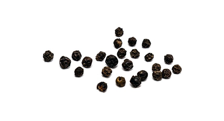 Photo des pois d'épices noires en gros plan sur un fond blanc