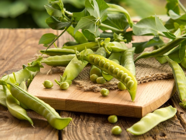 Pois frais et leurs cosses sur une vieille table en bois fond rustique avec des pois