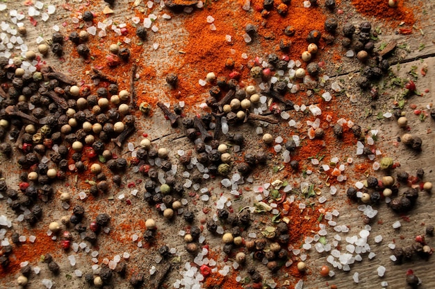 Pois poivre noir et blanc sel de mer poudre de poivre rouge clous de girofle épices sur fond de bois