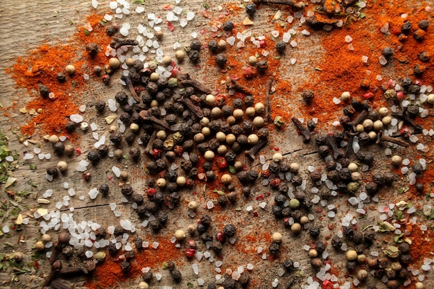 Pois poivre noir et blanc sel de mer poudre de poivre rouge clous de girofle épices sur fond de bois