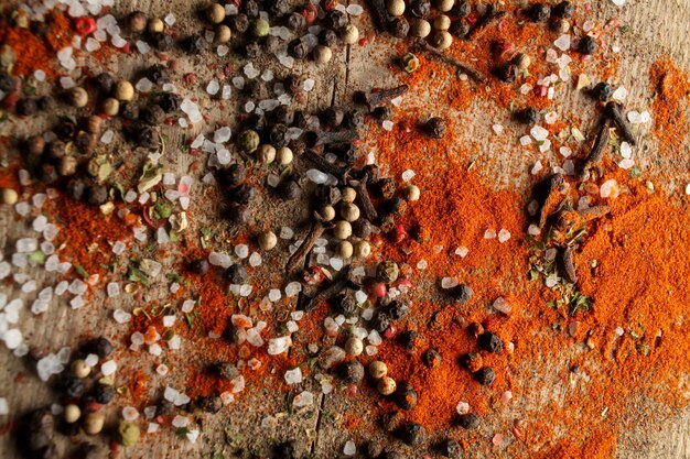 Pois poivre noir et blanc sel de mer poudre de poivre rouge clous de girofle épices sur fond de bois