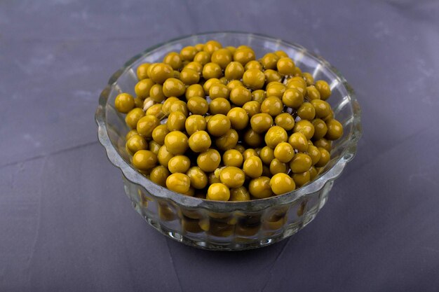 Pois verts en conserve dans un bol en verre sur fond gris