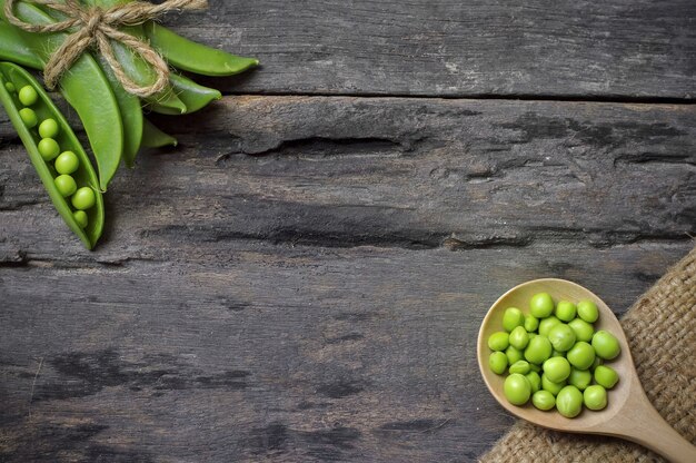 Pois verts à la cuillère en bois sur le vieux fond en bois