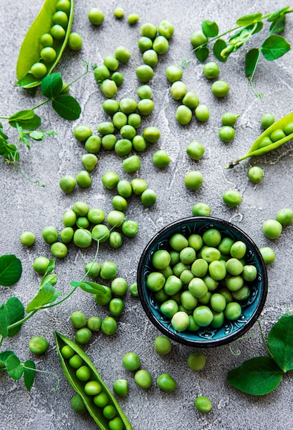 Pois verts dans une assiette sur un fond de béton gris. Vue d'en-haut.