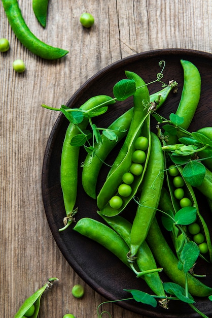 Pois verts dans une assiette sur une vieille surface en bois