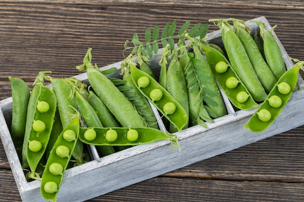 pois verts dans une boîte grise en bois (gros plan)