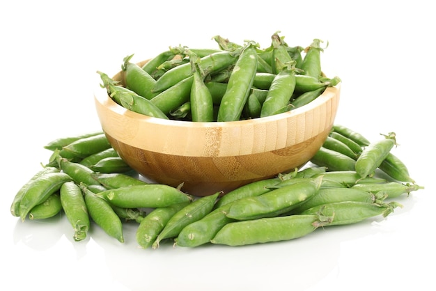 Pois verts dans un bol en bois isolé sur blanc