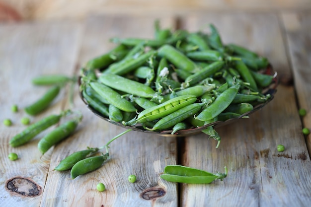 Pois verts dans un bol sur une surface en bois