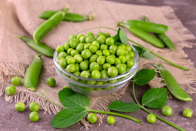 Pois verts dans un bol en verre sur une table grise