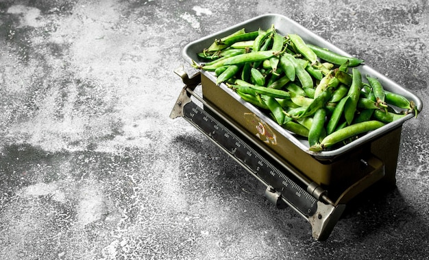 Pois verts sur les échelles sur une table rustique.