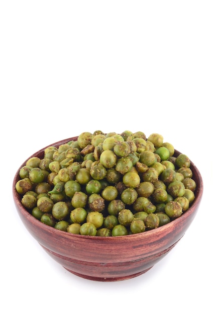 Pois verts frits épicés {chatpata matar} Snack indien. Pois verts salés séchés dans un bol en bois avec cuillère sur fond blanc