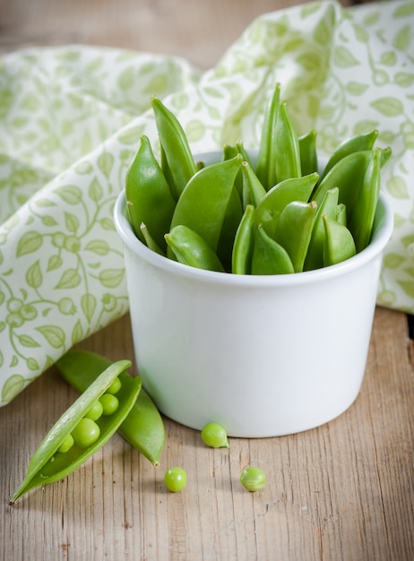 Pois verts en gousses sur table en bois