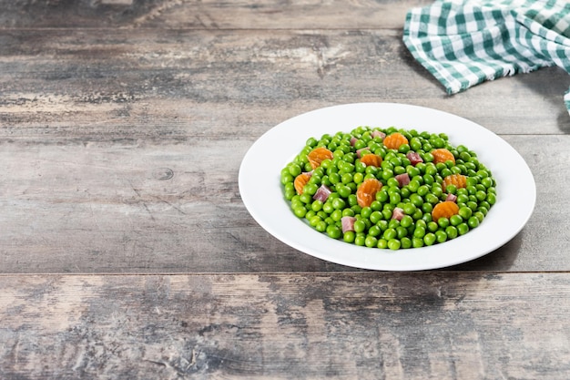 Pois verts avec jambon serrano et carotte sur table en bois