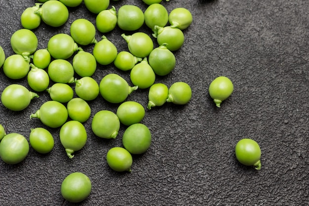 Pois verts pelés sur table. Fond noir. Mise à plat