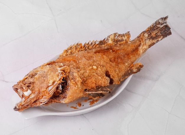 Un poisson sur une assiette frit lapu lapu poisson frit complet poisson alevins dans une assiette