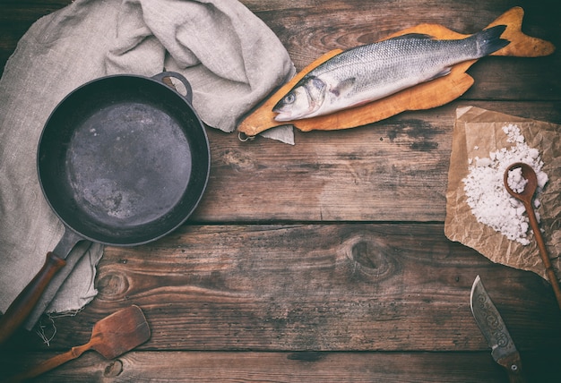 Poisson de bar entier frais sur une planche à découper brune