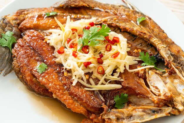 Poisson de bar frit avec sauce de poisson et salade épicée sur plaque