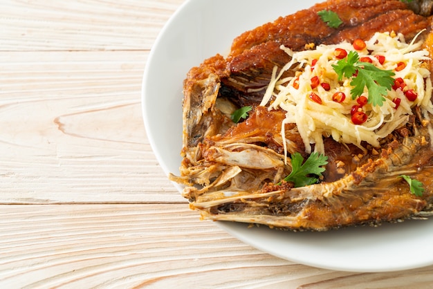 Poisson de bar frit avec sauce de poisson et salade épicée sur plaque