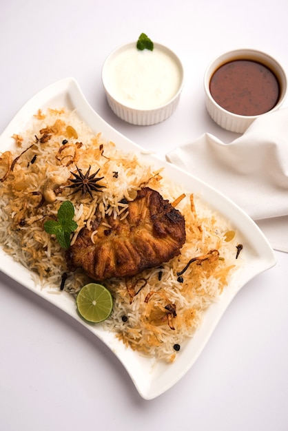 Poisson Biryani authentique servi dans une assiette blanche sur fond blanc, mise au point sélective