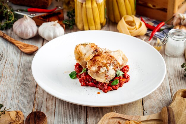 Poisson blanc frit avec ragoût de légumes à la sauce rouge sur la table en bois