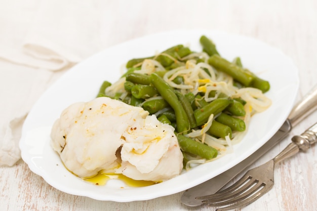 Poisson bouilli avec haricots verts sur plat blanc