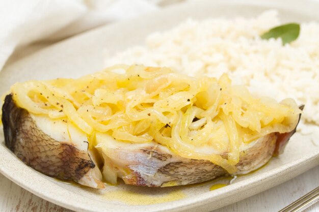 Poisson bouilli avec oignon et riz bouilli sur plaque blanche