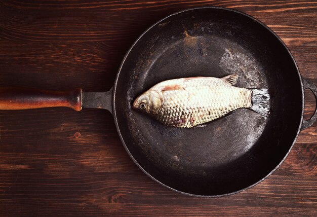 Poisson carpe frais dans une poêle en fonte noire