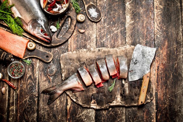 Poisson cru. Couper les mains des femmes de saumon frais. Sur la vieille table en bois.