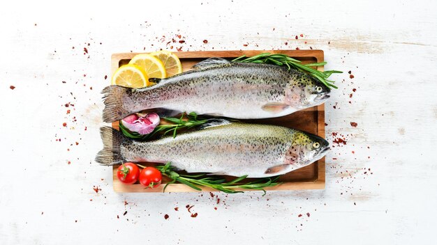 Poisson cru avec des légumes sur un fond en bois blanc Truite de poisson Vue de dessus Espace libre pour votre texte