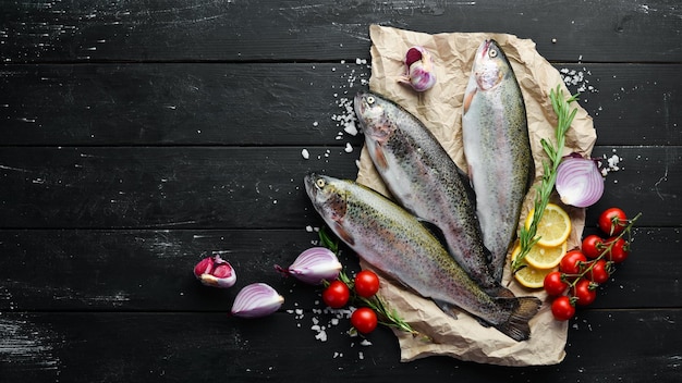 Poisson cru avec des légumes sur un fond en bois noir Truite de poisson Vue de dessus Espace libre pour votre texte