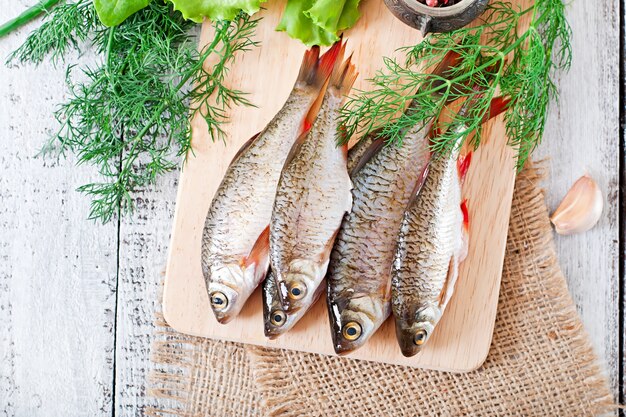 Photo poisson cru sur une planche à découper avec des herbes