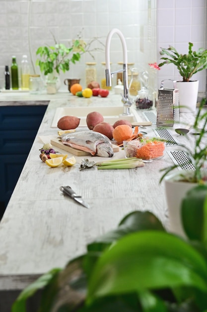 Poisson cru pour cuisiner avec des légumes sur la table de la cuisine.