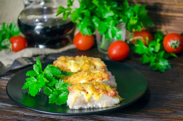 poisson cuit avec des légumes et du fromage dans une sauce blanche sur fond sombre