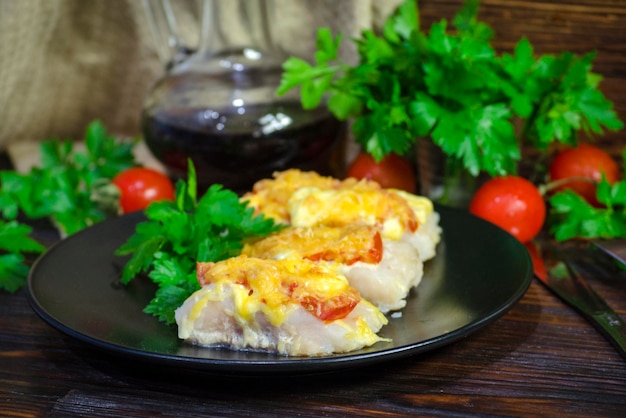 Photo poisson cuit avec des légumes et du fromage dans une sauce blanche sur fond sombre