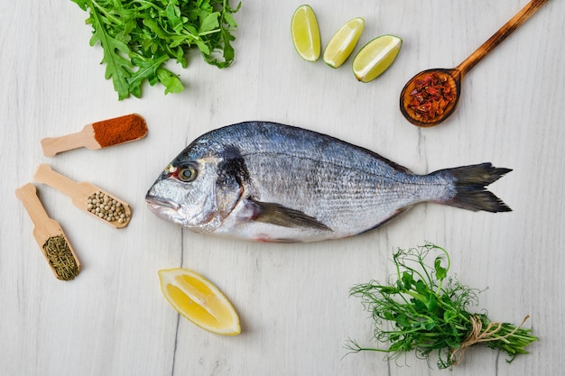 Poisson Dorada sur la table avec des épices et des herbes