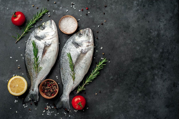 Poisson dorade cru aux épices et ingrédients tomate, razmorine, huile de tournesol, citron sur un fond de pierre avec espace de copie pour votre texte