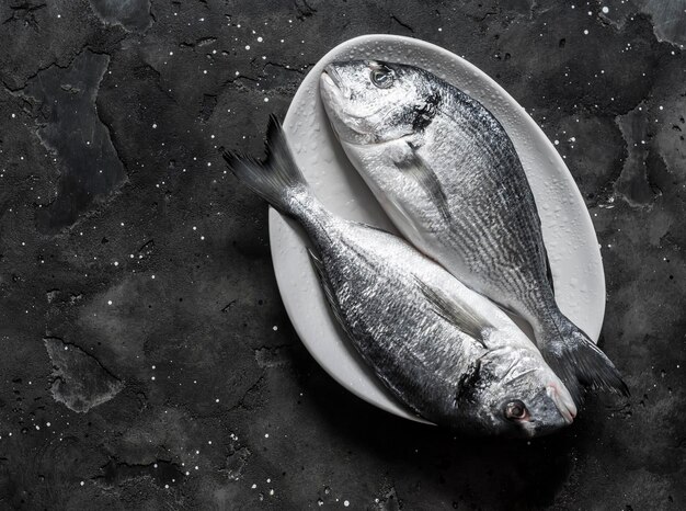 Poisson dorado cru frais sur fond sombre vue de dessus Ingrédients de régime alimentaire