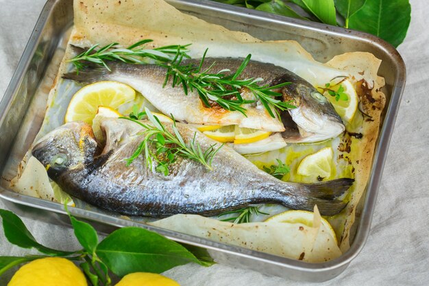 Poisson dorado dorada de mer rôti grillé frais avec de l'huile d'olive aux herbes d'origan au citron et au romarin sur la table de la cuisine