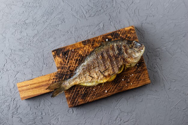 Poisson Dorado farci au citron et aux épices sur une planche en bois