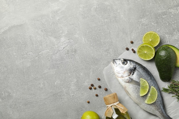 Poisson Dorado et ingrédients de cuisine sur fond gris, vue de dessus