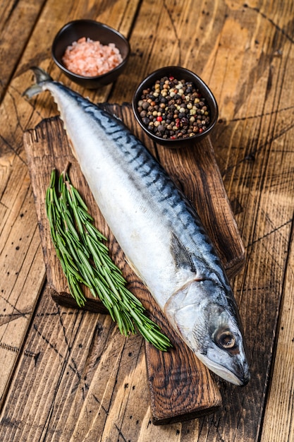 Poisson d'eau salée cru Maquereau sur une planche à découper en bois avec un thym. fond en bois. Vue de dessus.